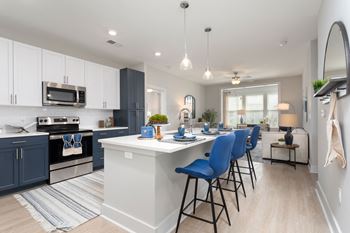 an open kitchen with an island and blue bar stools at Bristol at New Riverside, Bluffton